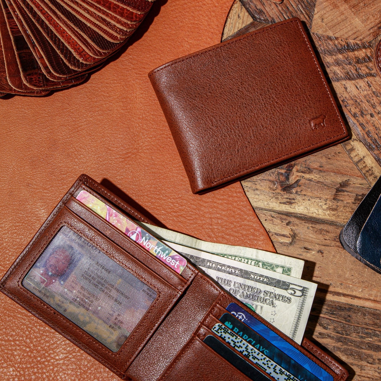 Brown leather bifold wallet open showing card slots and cash compartment on wooden surface