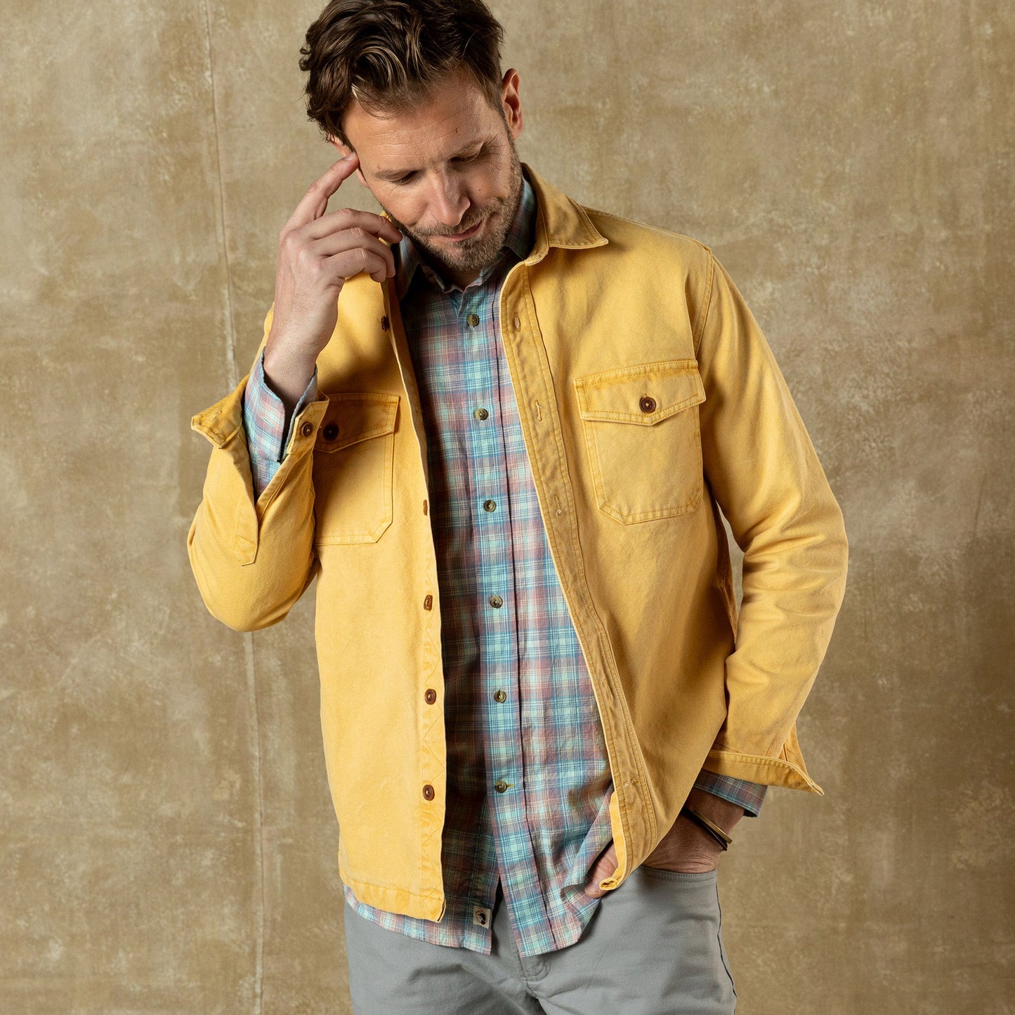 Man wearing yellow duck canvas jacket over plaid shirt in professional lifestyle photo