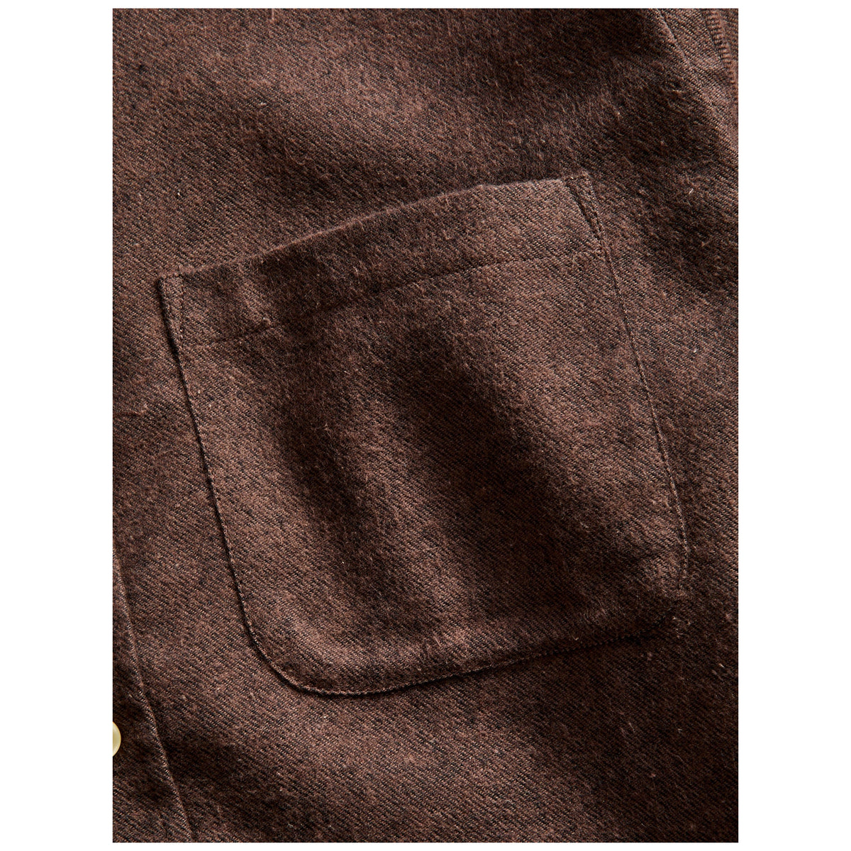 Close-up detail of brown flannel shirt chest pocket with visible twill weave texture