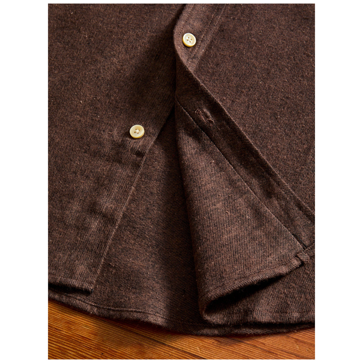 Close-up detail of brown flannel shirt showing cream buttons and fabric texture