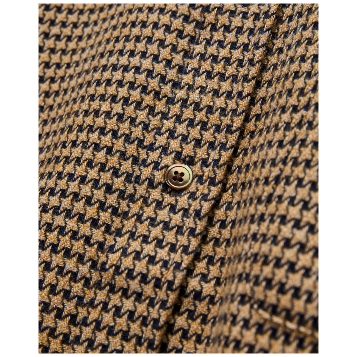 Close-up detail of houndstooth flannel shirt with gold button in camel and navy