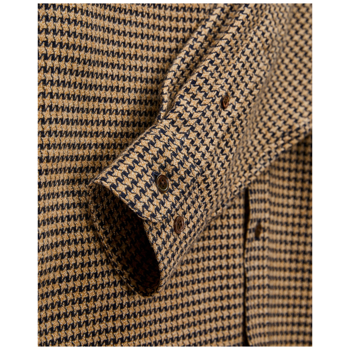 Close-up detail of houndstooth flannel shirt cuff with brown buttons in camel and navy