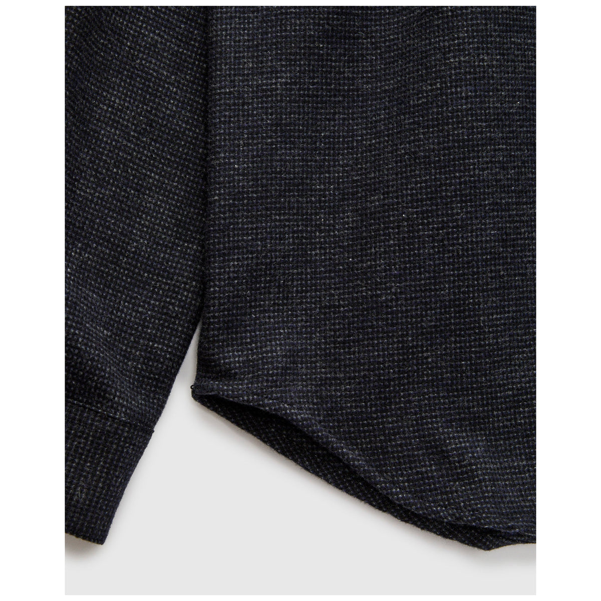 Close-up detail of dark navy charcoal tweed textured flannel fabric hem and sleeve
