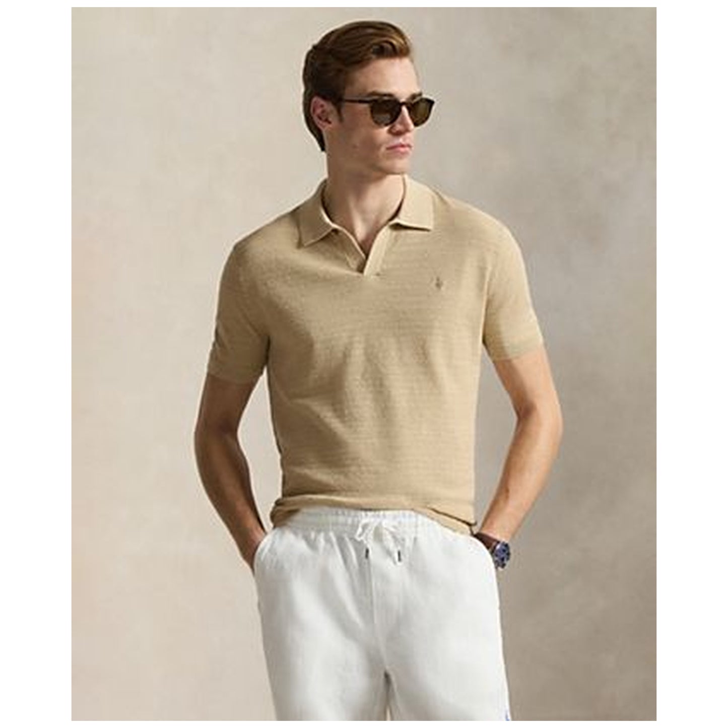 Man wearing tan cotton sweater polo shirt with white pants and sunglasses