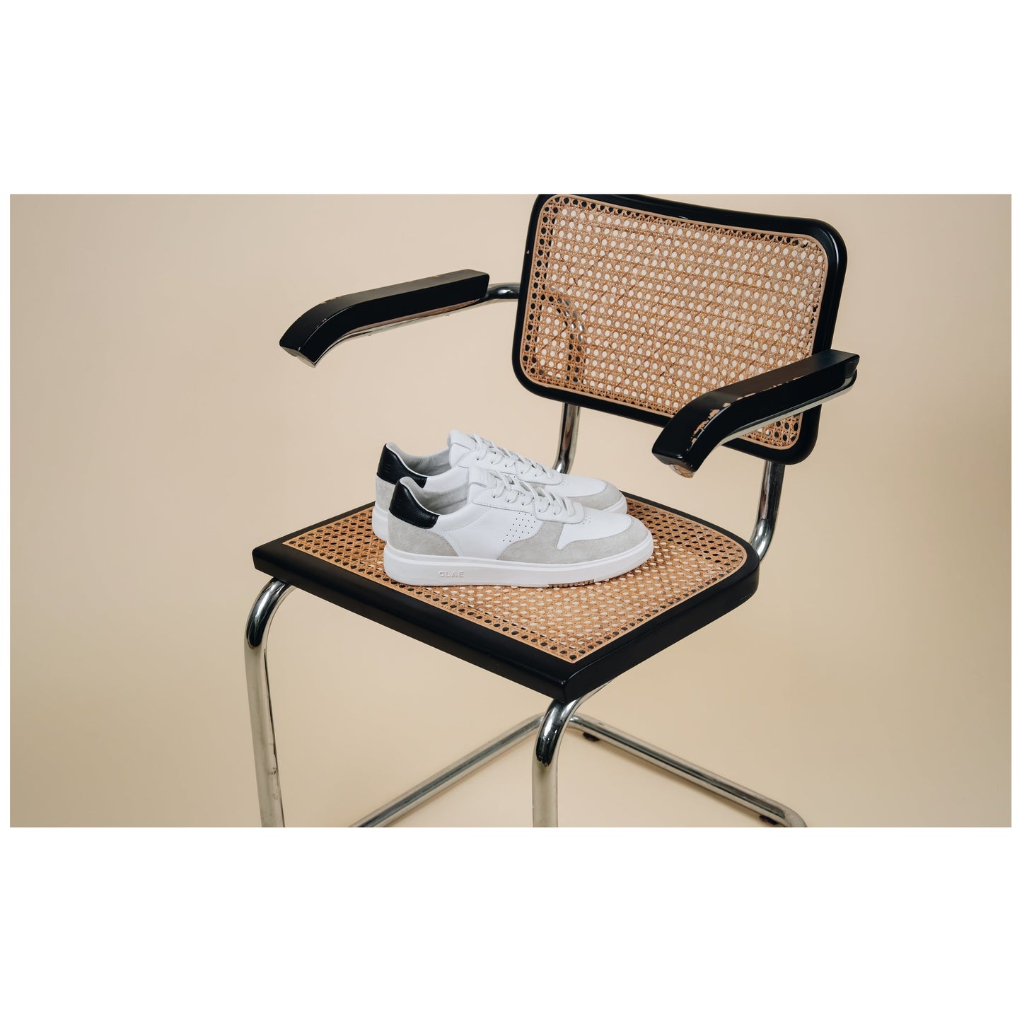 White Clae Bradley sneakers with gray accents on modern cane chair