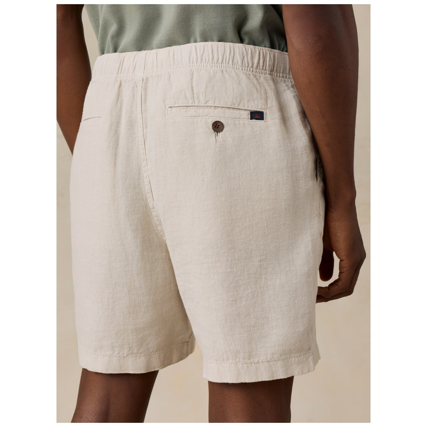 Model wearing beige linen shorts with elastic waistband and back pocket detail