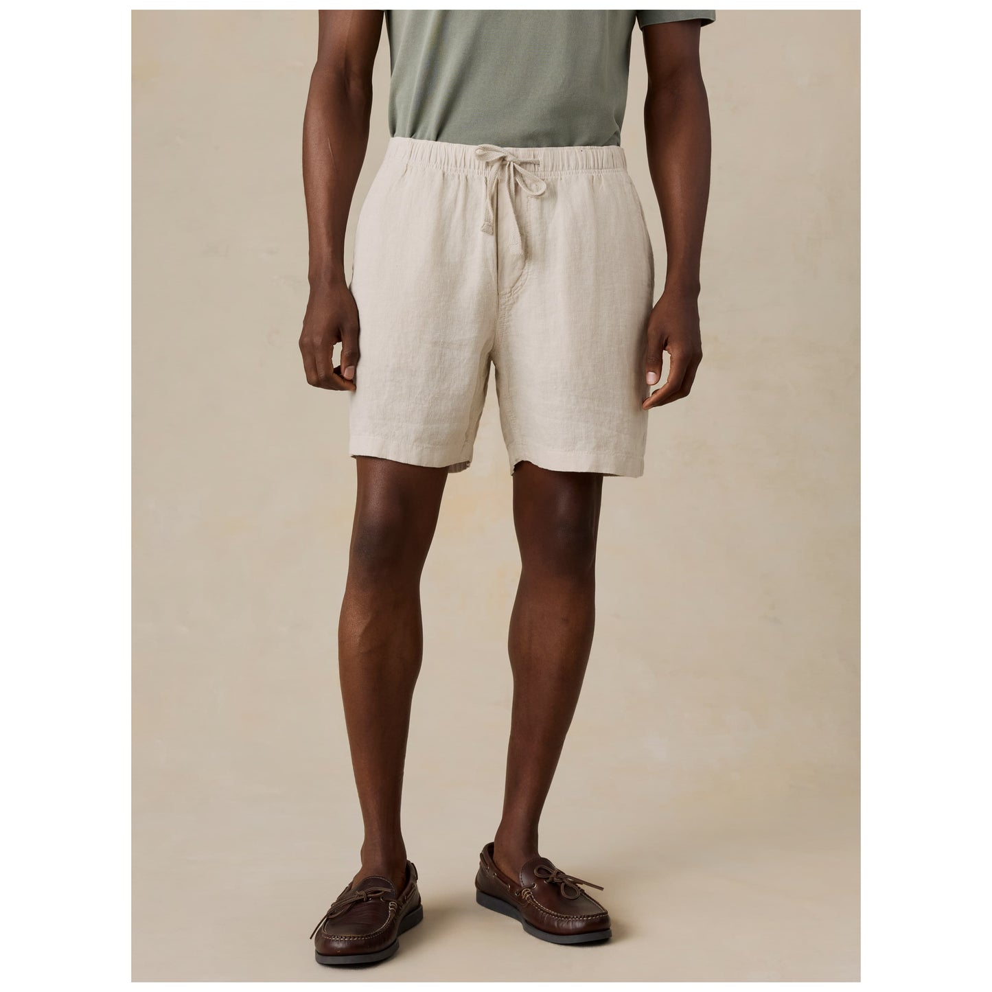 Model wearing beige linen shorts with drawstring waist and boat shoes