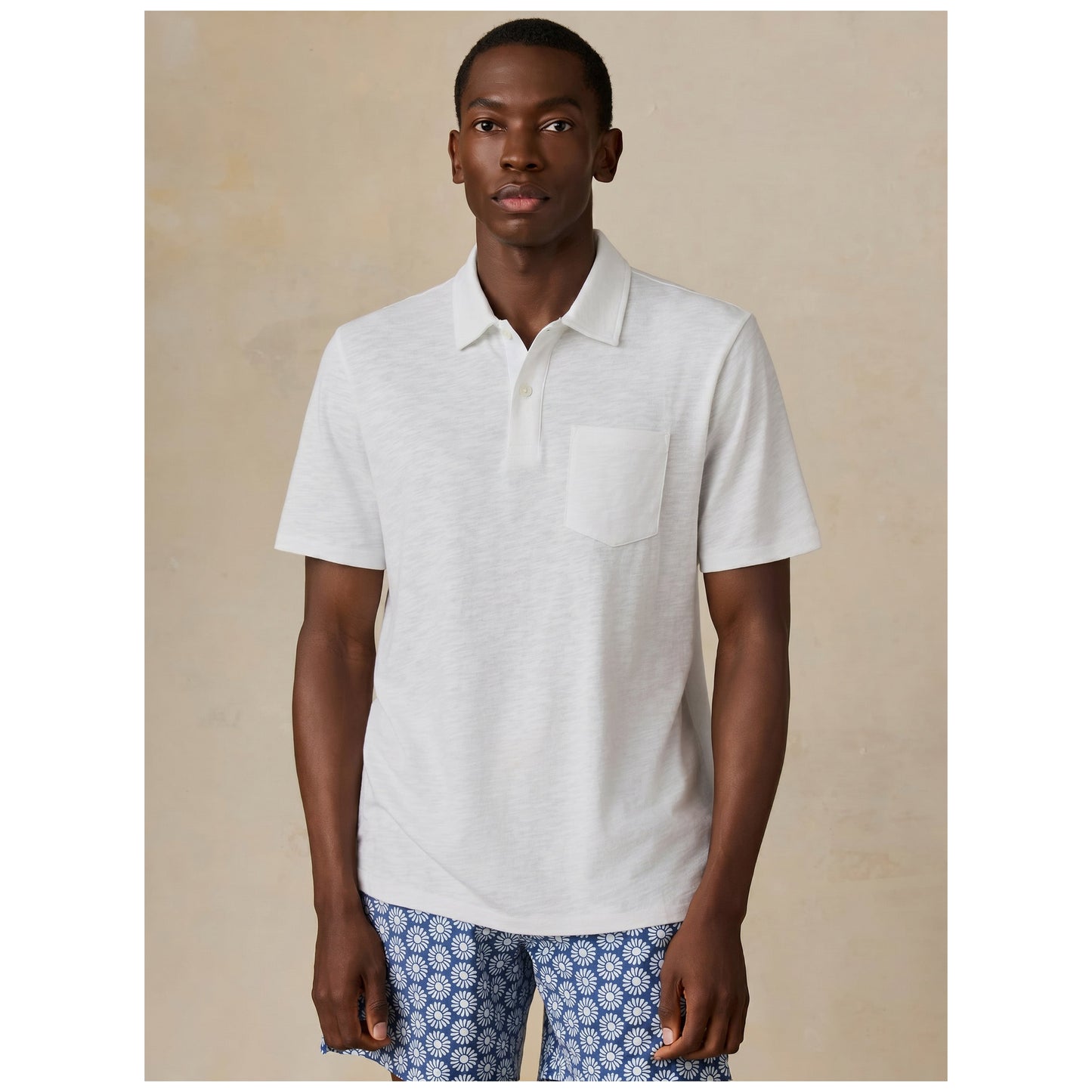 Model wearing white short-sleeve polo shirt with blue patterned shorts