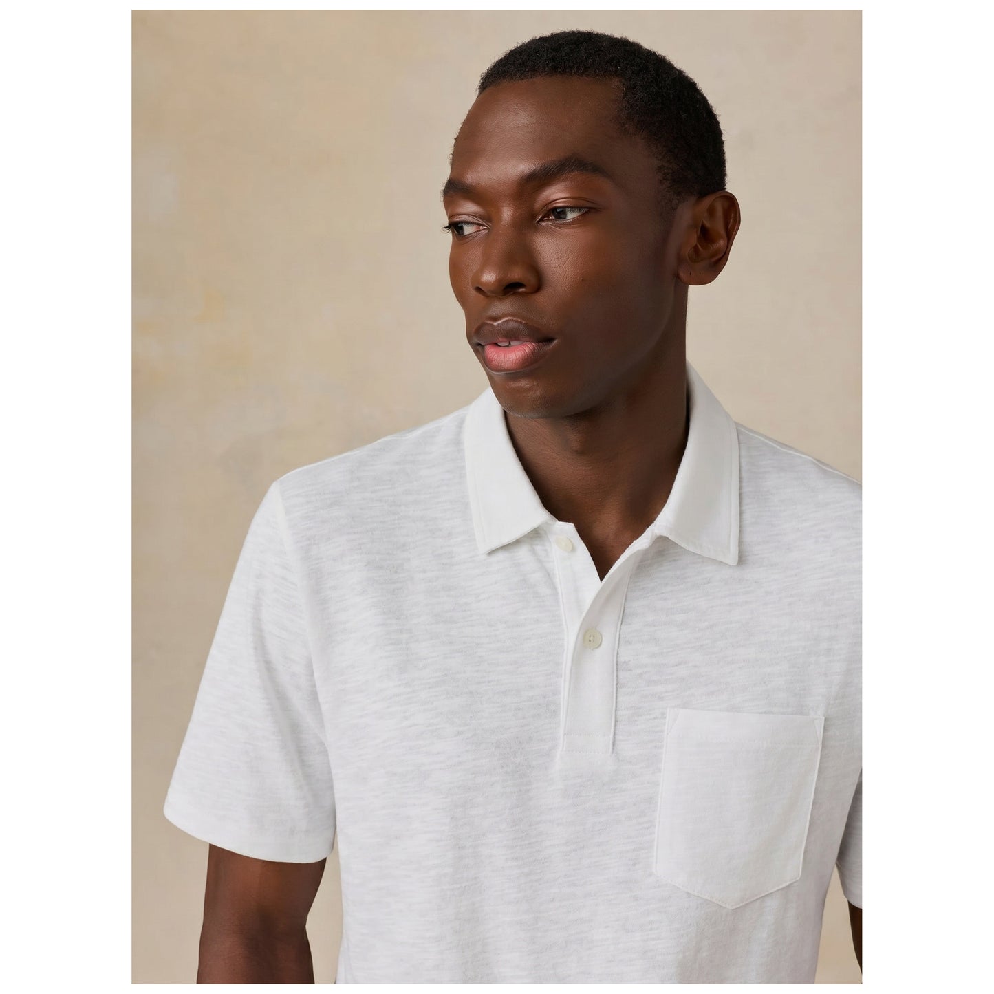 Male model wearing white short-sleeve polo shirt against neutral background