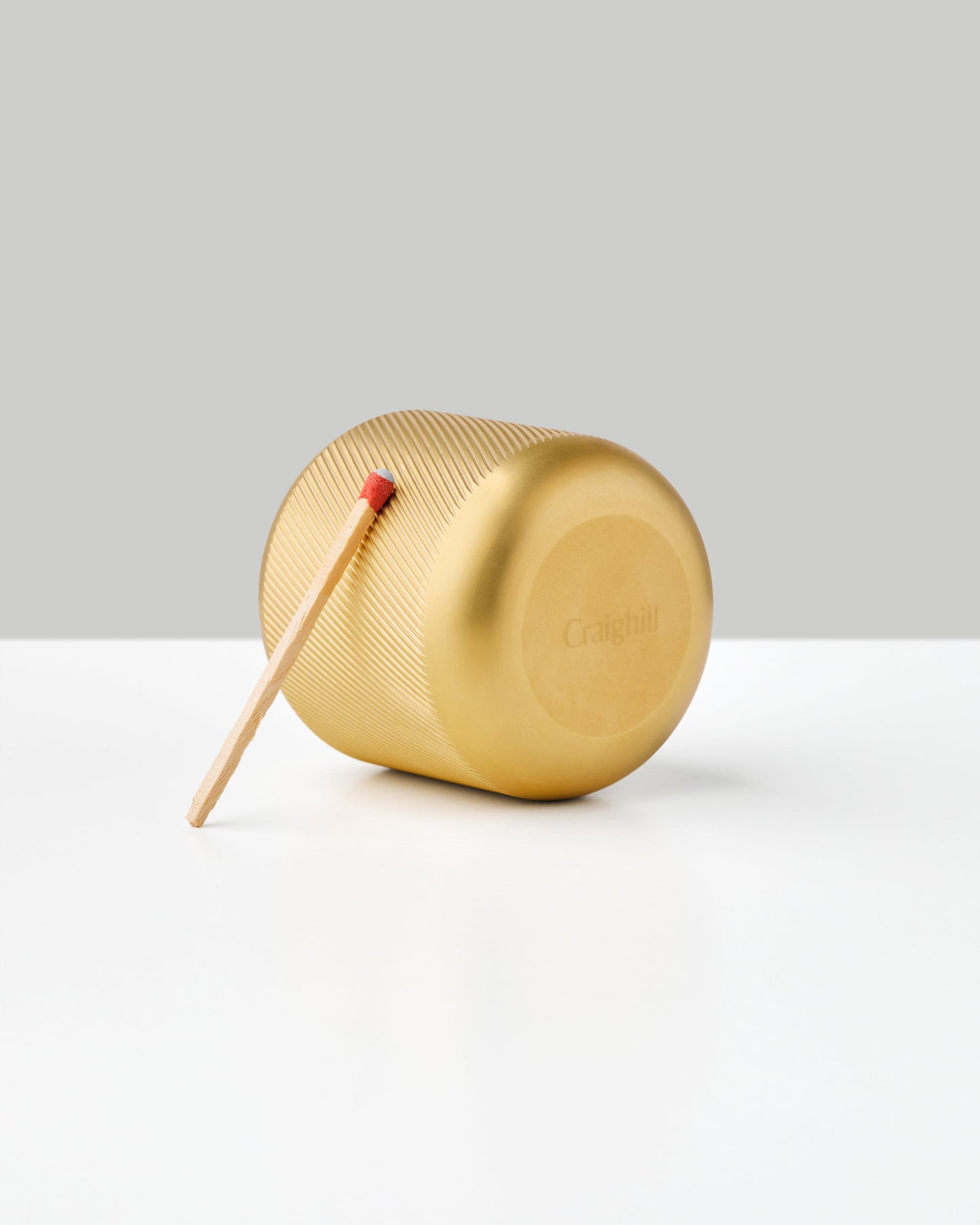 Gold brass cylindrical match striker with ridged surface and wooden match stick