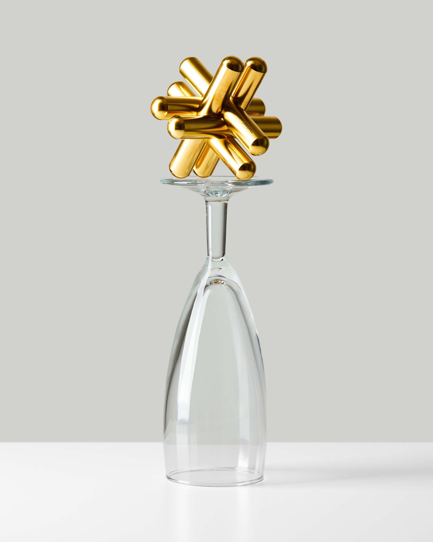 Craighill brass Jack puzzle balanced artistically on clear glass bottle neck