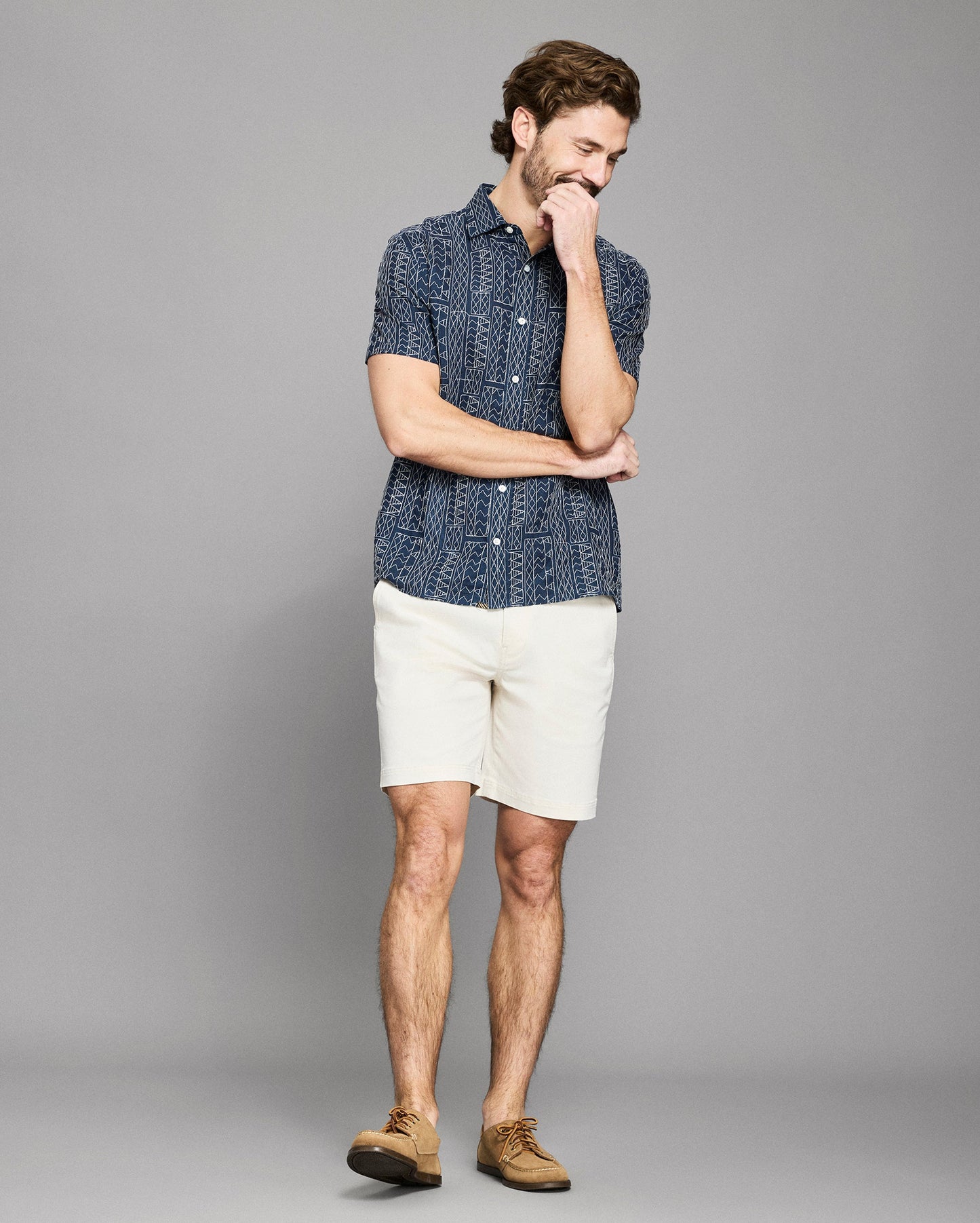 Man wearing navy blue geometric patterned short sleeve shirt with white shorts