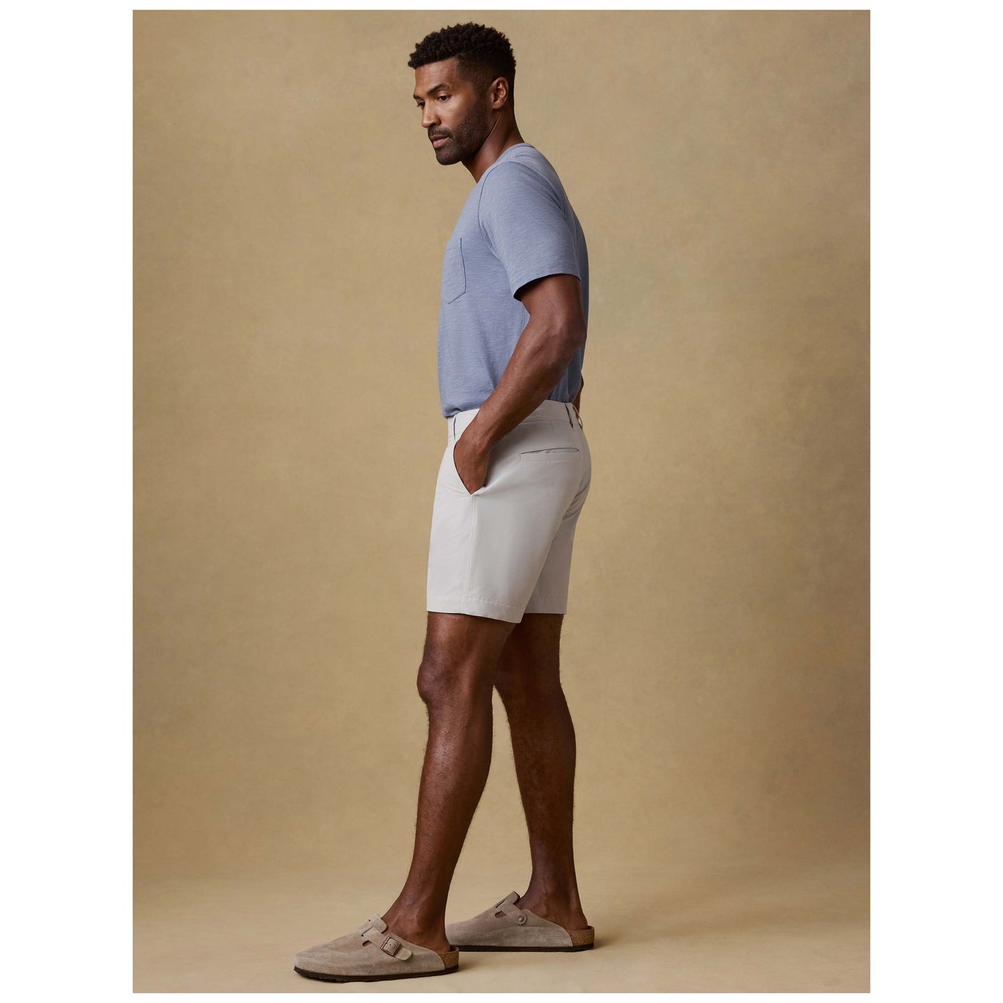 Male model wearing stone colored All Day Shorts with gray t-shirt and sandals